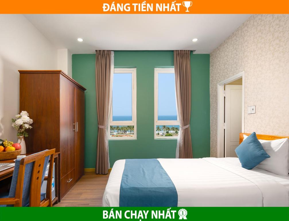 a bedroom with a bed and a desk and two windows at Shara Hotel Da Nang in Da Nang