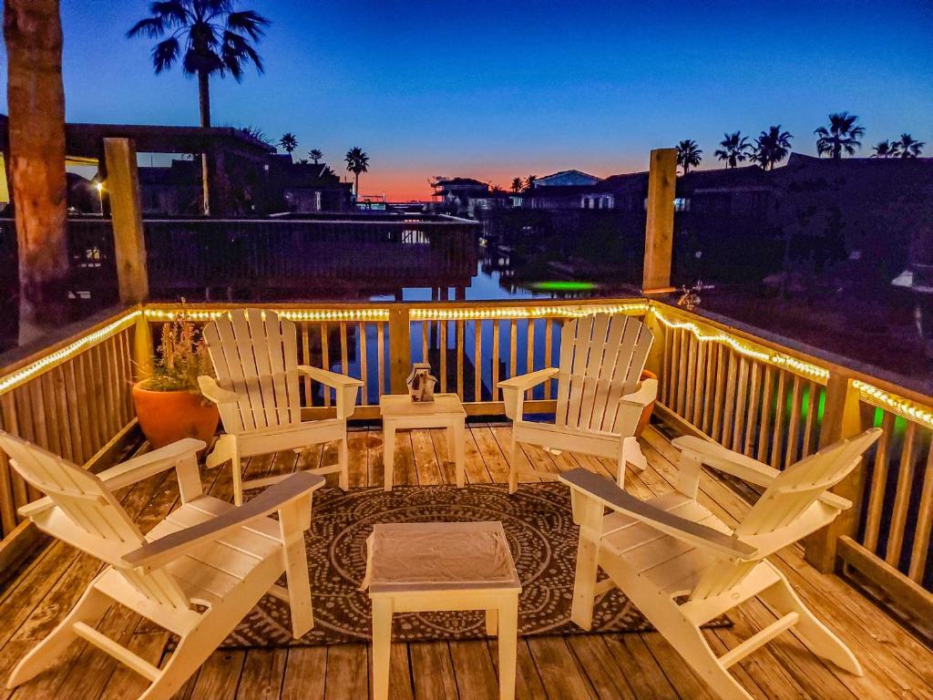 a deck with chairs and a table and a sunset at Herons Nest by VTrips in Galveston
