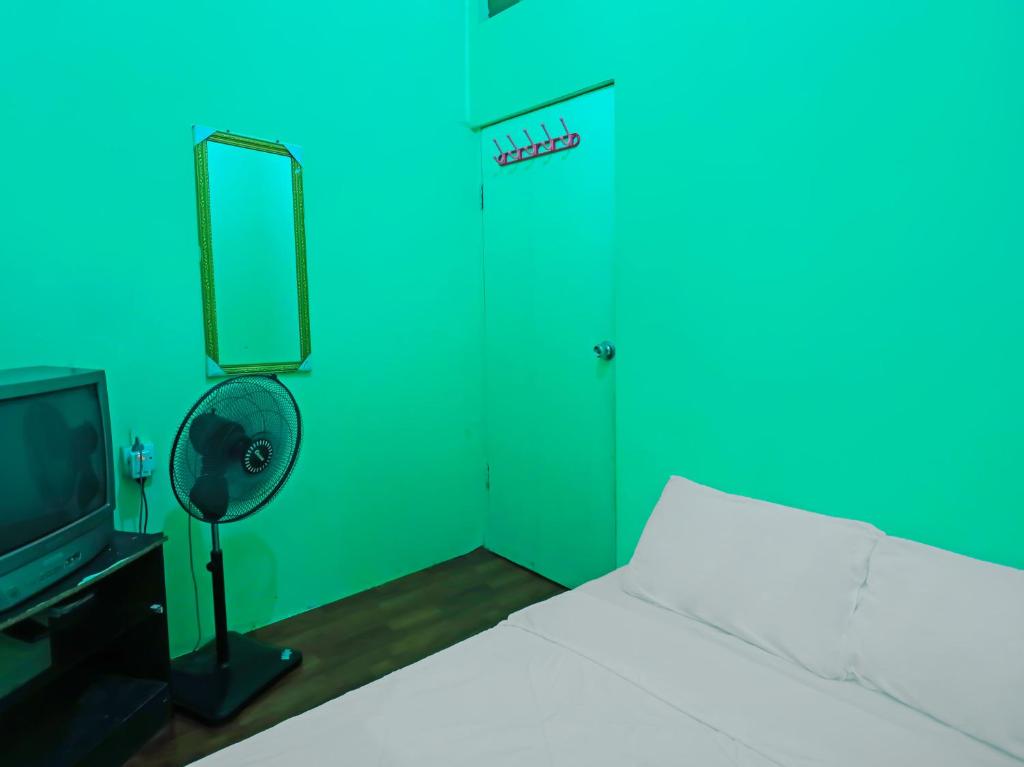 a bedroom with a bed and a television and a green door at SPOT ON 92538 Joyoakis Homestay Syariah in Nagoya