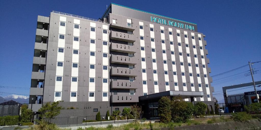 a large white building with a sign on it at Hotel Route-Inn Yamanashi Chuo in Chuo