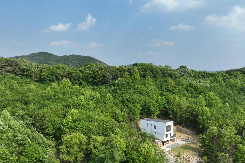 a white house in the middle of a forest at SunnyVille 90 in Yangpyeong