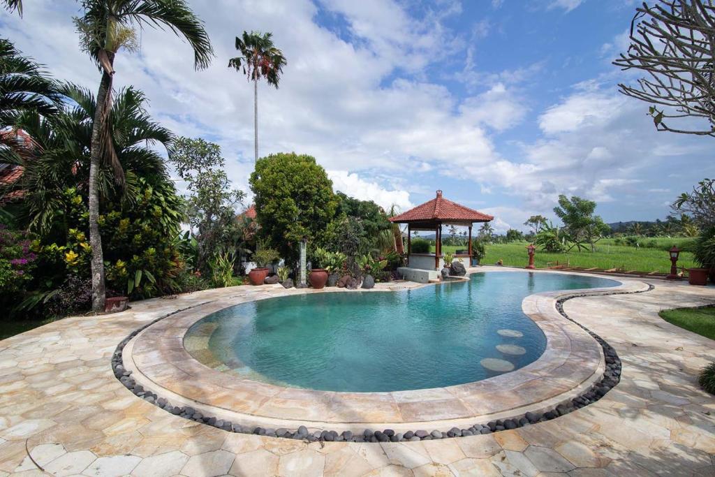 a swimming pool in a yard with a gazebo at Cabé Bali in Jasri