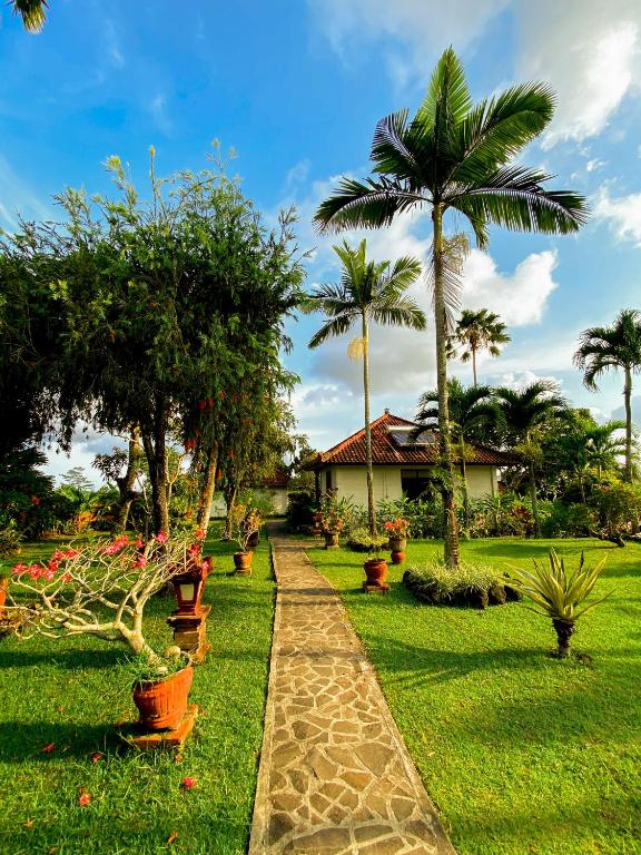 a garden with palm trees and a walkway at Cabé Bali in Jasri