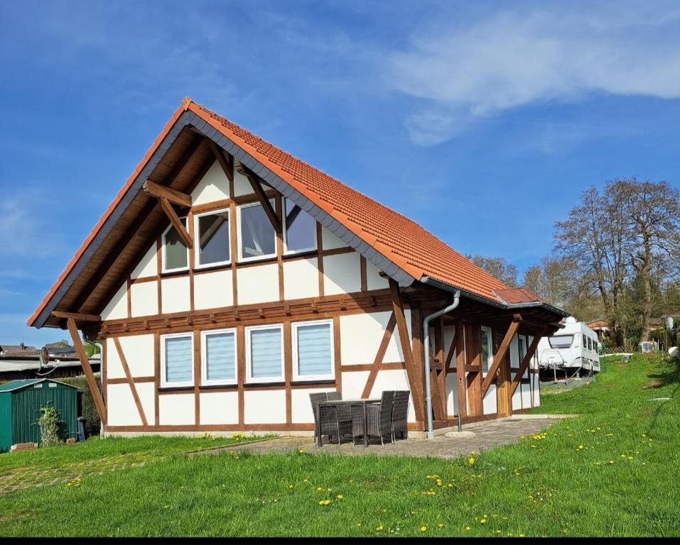 ein Haus mit einem orangenen Dach auf einem grünen Feld in der Unterkunft HM - Ferienhaus 3 Deluxe Krombachtalsperre Westerwald exklusive verbrauchte NK in Driedorf