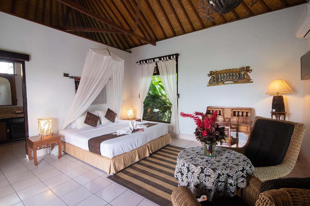 a bedroom with a bed and a table and chairs at Cabé Bali in Jasri