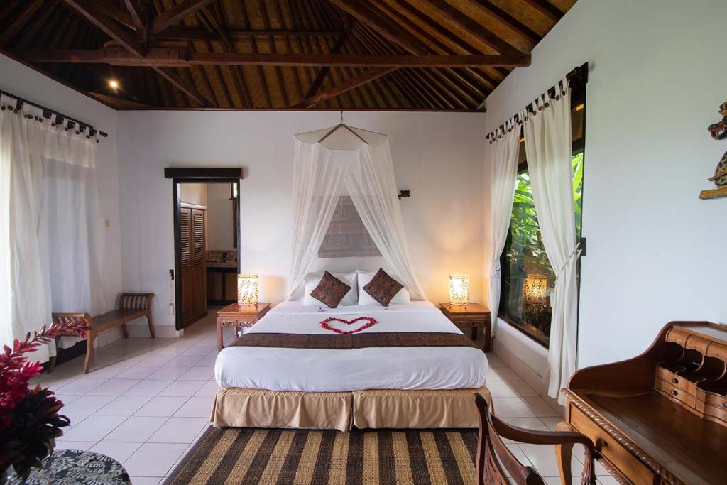 a bedroom with a bed with a heart on it at Cabé Bali in Jasri