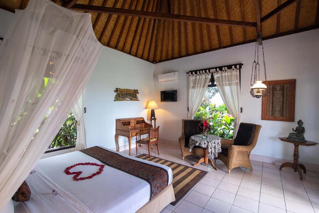a bedroom with a bed and a desk in a room at Cabé Bali in Jasri