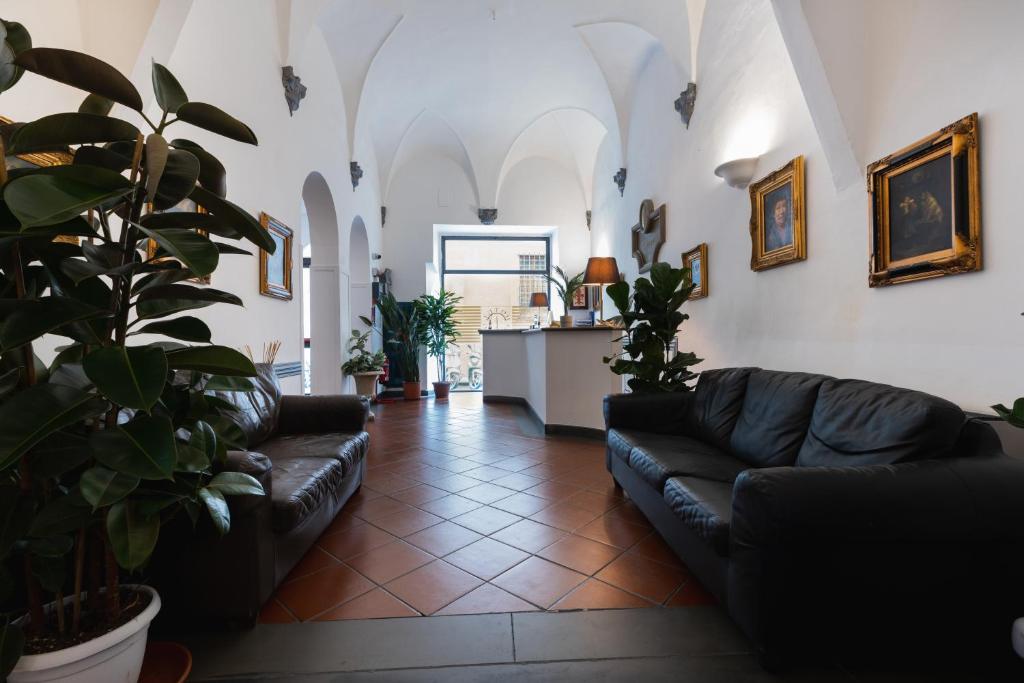 a living room with black leather couches and plants at Hotel Unicorno in Florence