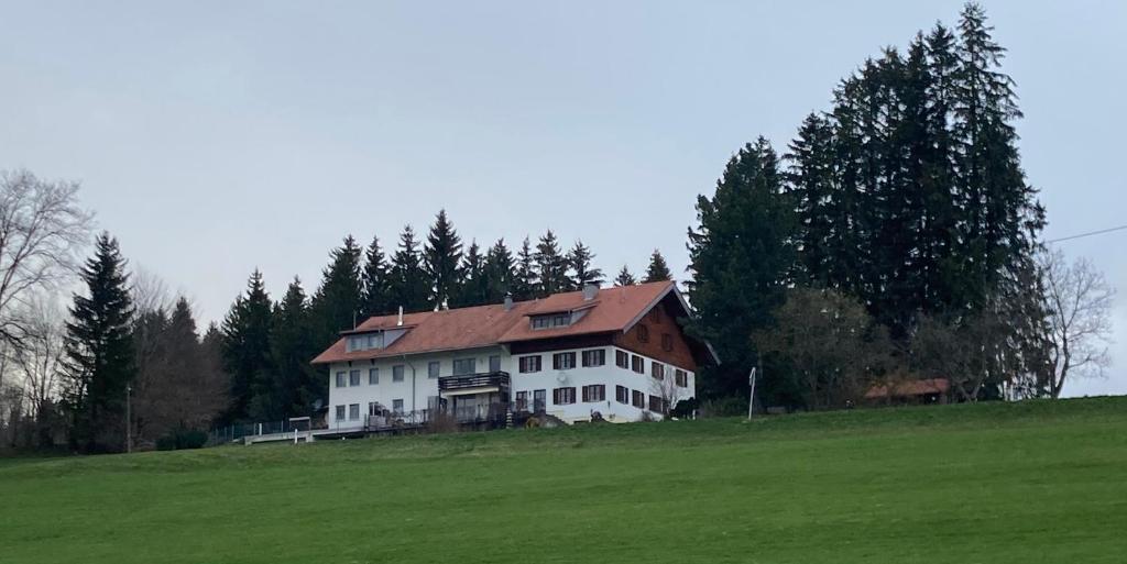 une grande maison blanche sur une colline dans un champ dans l'établissement Säntisblick, à Weitnau