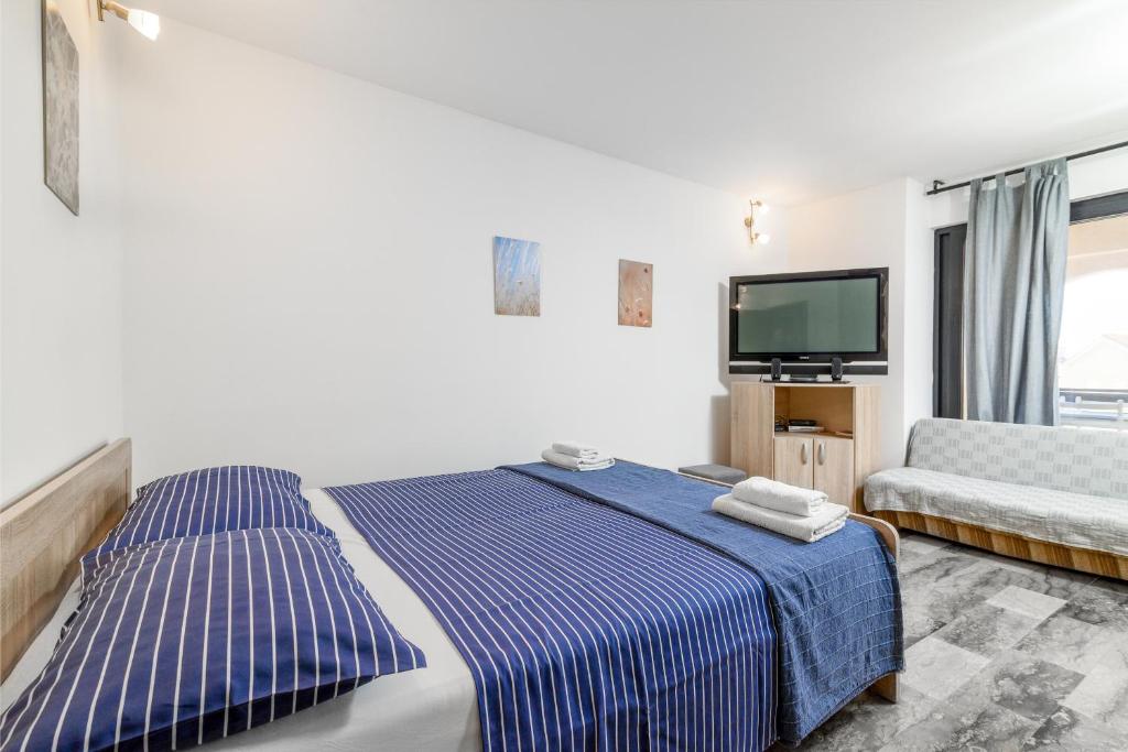 a bedroom with a bed and a couch and a tv at Apartment Premantura 2228a in Premantura