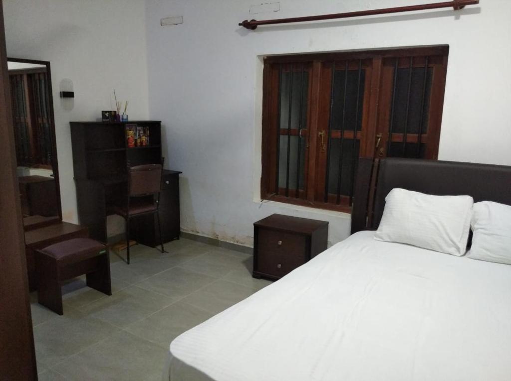 um quarto com uma cama, uma mesa e uma cadeira em Sweet Pea Hostel em Balapitiya
