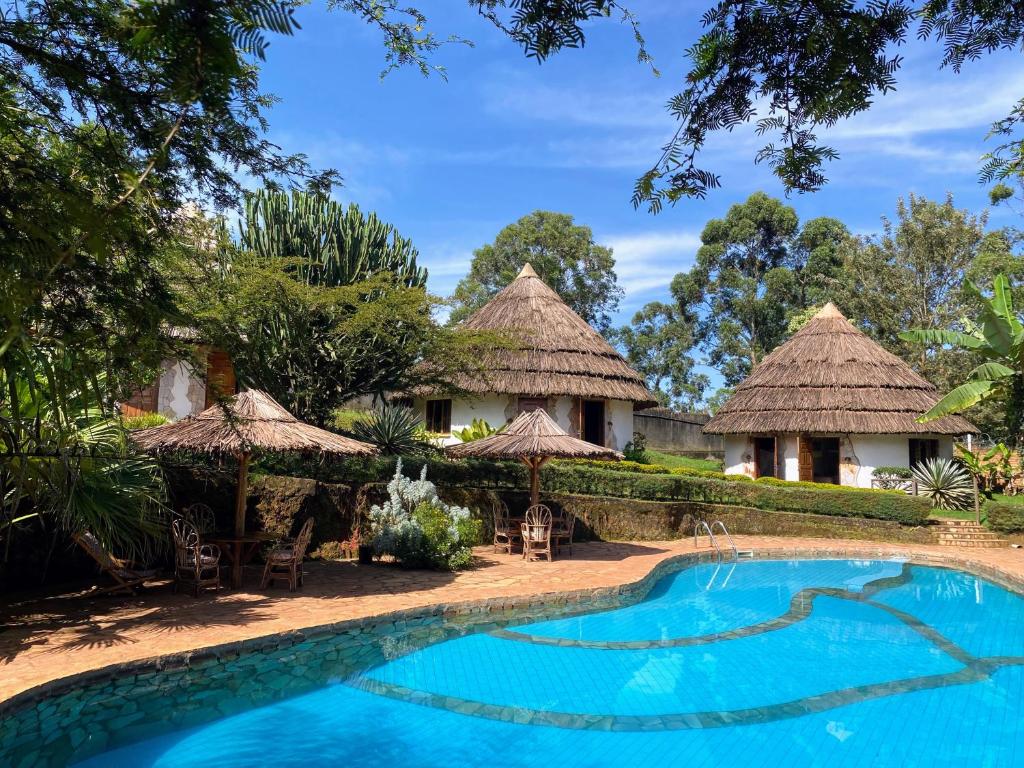ein Resort mit einem Pool und strohgedeckten Hütten in der Unterkunft Banda Lodge in Masaka
