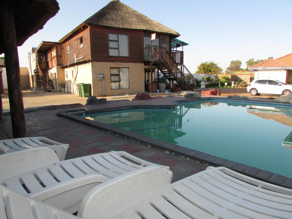 einen Pool mit zwei Liegestühlen und ein Haus in der Unterkunft Kea-Resort in Hammanskraal next to Dinokeng Game Reserve in  Hammanskraal 