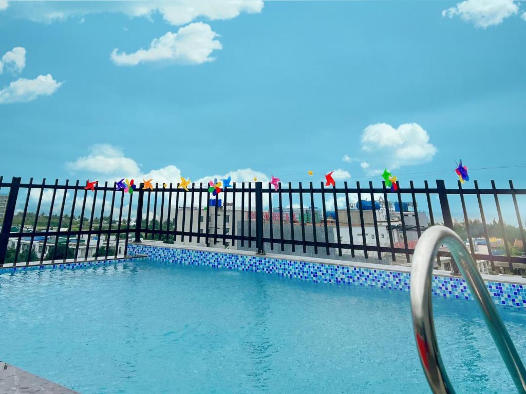 - une piscine avec une clôture noire et de l'eau dans l'établissement Tuấn Đạt Luxury FLC Sầm Sơn, à Sầm Sơn