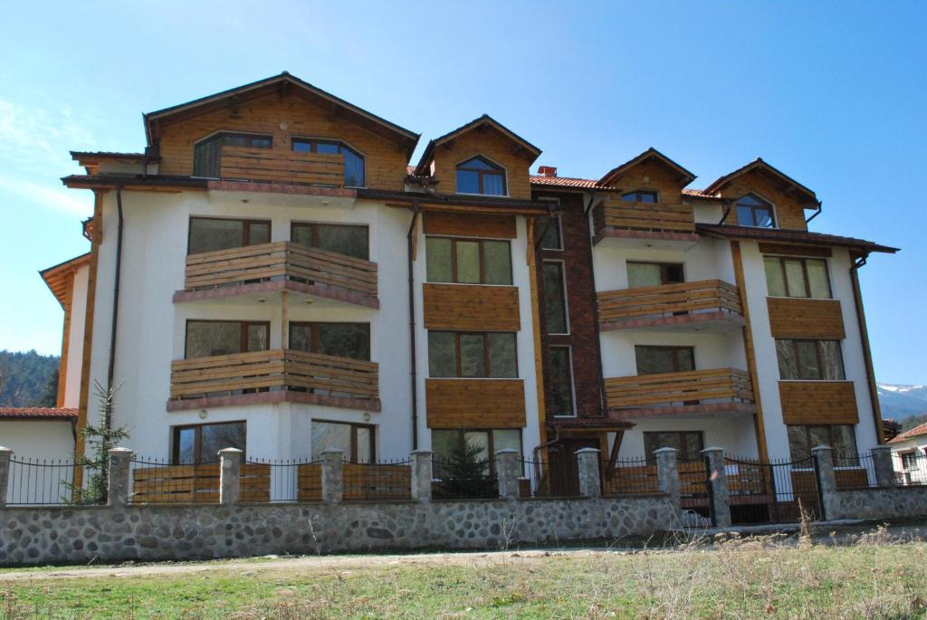 a large house with wooden balconies on top of it at PM Services Riverside Apartments in Madzhare