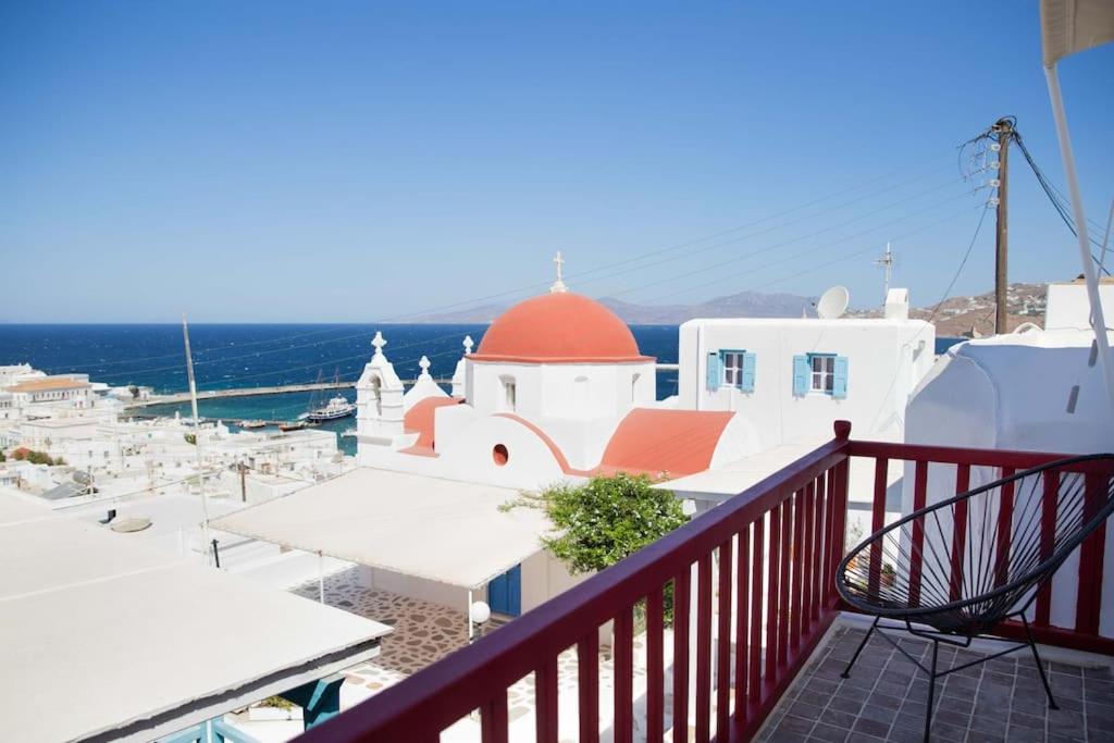 a balcony with a view of a church and the ocean at Mooi Boni's in Mikonos