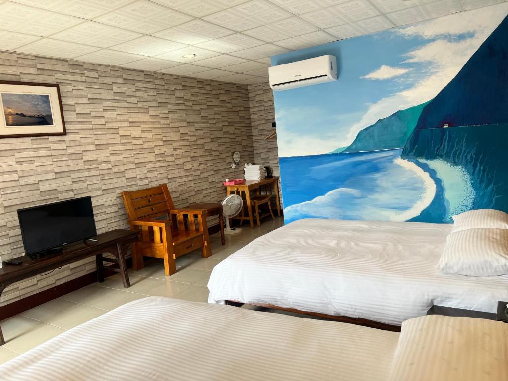 a bedroom with two beds and a painting on the wall at Golden flower Homestay in Yuli