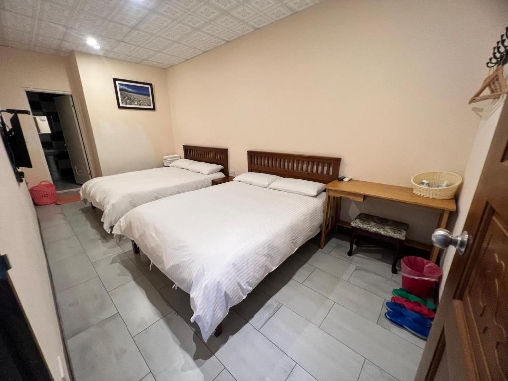a bedroom with two beds and a desk and a table at Golden flower Homestay in Yuli