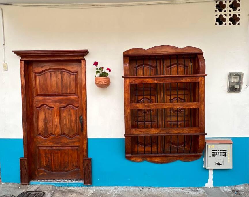 two wooden doors next to a wall with a plant at Apartamento a 5 minutos del parque principal in Jardin