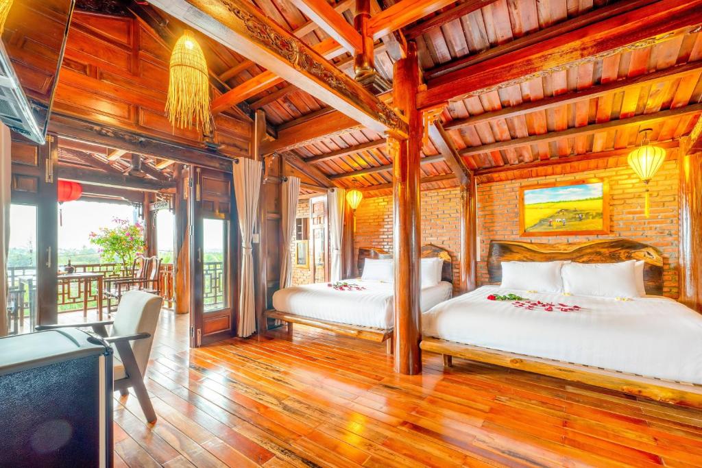 Eco Wooden villa Hoi An في هوي ان: سريرين في غرفة بسقوف خشبية
