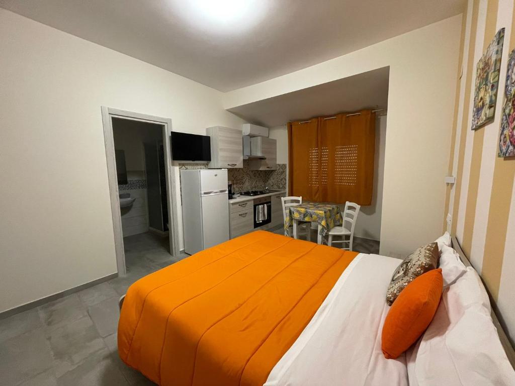 a bedroom with an orange bed and a kitchen at Le Camere Del Villaggio in Agrigento