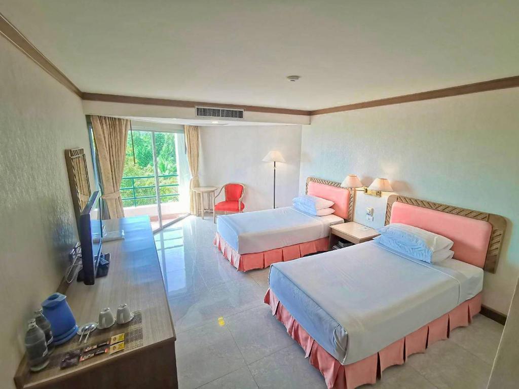 ein Hotelzimmer mit zwei Betten und einem Fernseher in der Unterkunft Khanom Golden Beach Hotel in Khanom