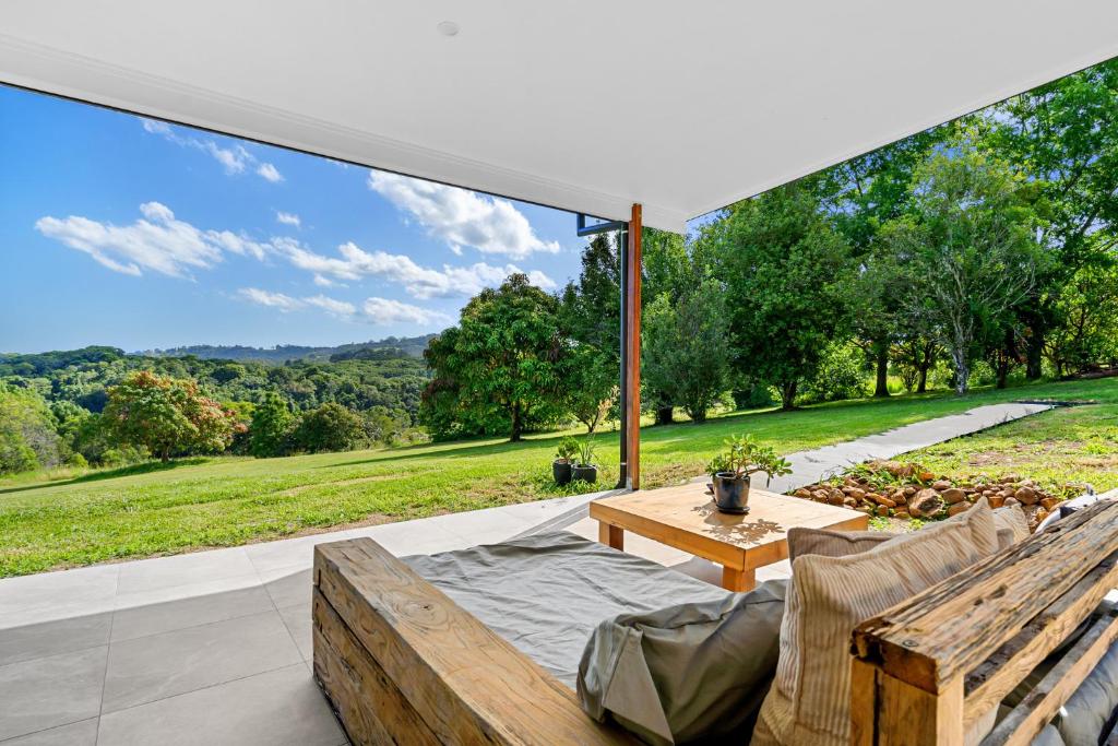 a patio with a table and chairs and a large window at Gan Eden Retreat-Byron bay , luxuries escape in Mullumbimby
