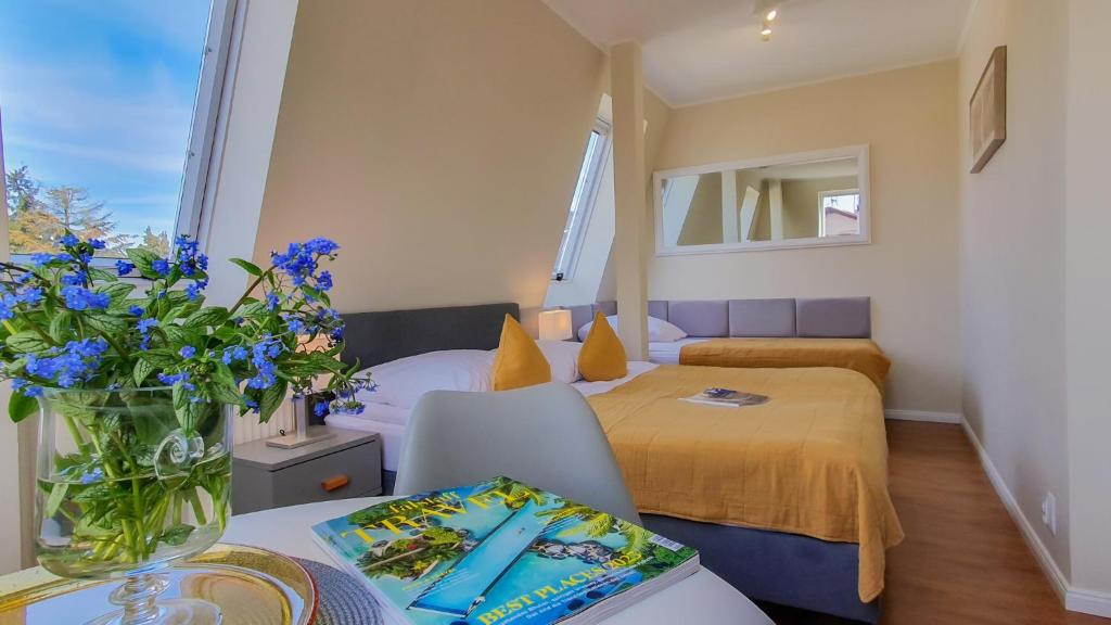 Un dormitorio con una cama y una mesa con un jarrón de flores en Villa Elefant, en Międzyzdroje