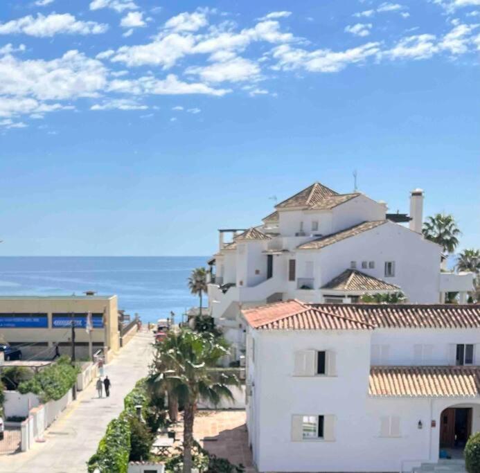 ein weißes Gebäude neben einem Strand mit Meer in der Unterkunft La Cala de Mijas - Playa y parque a unos pasos in La Cala de Mijas