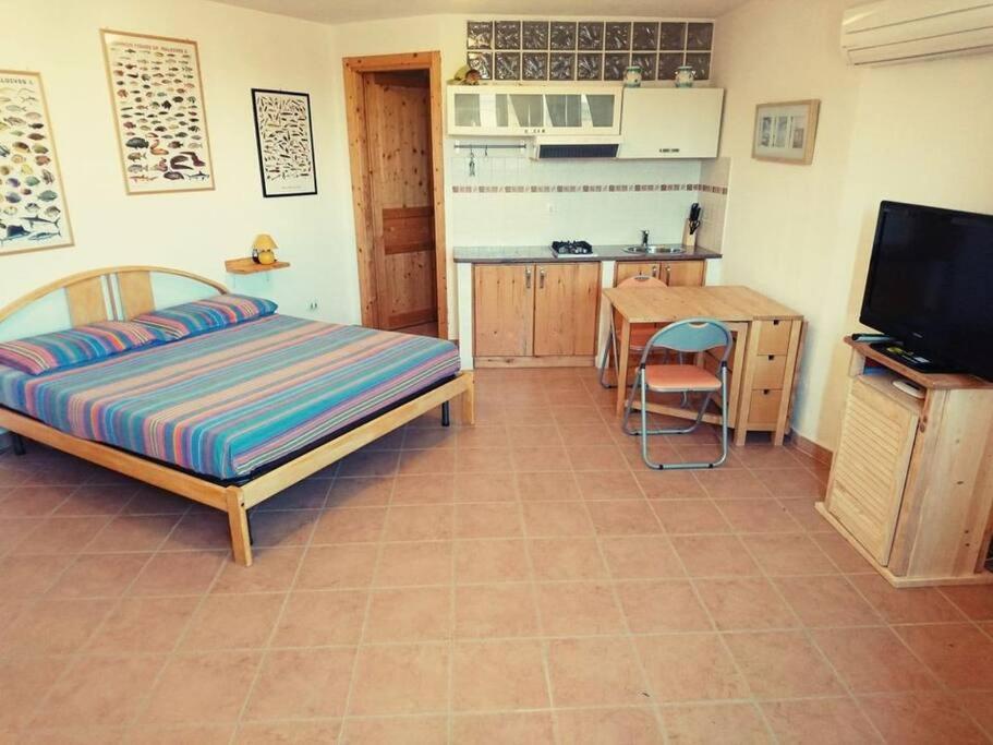 a bedroom with a bed and a table and a kitchen at Monolocale La Maddalena in La Maddalena