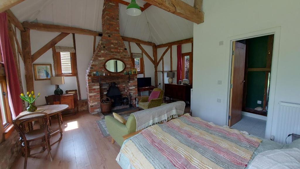 a living room with a bed and a brick fireplace at Brooklands Barn in Lower Swanwick