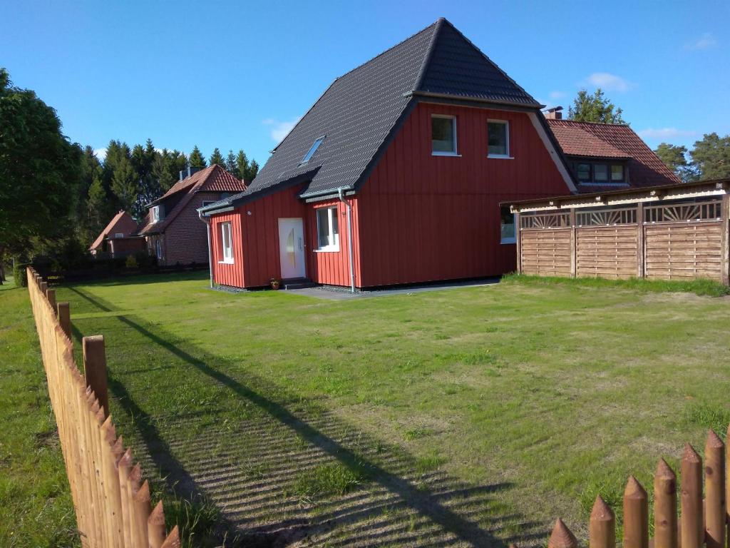 a red house with a fence in a yard at Ferienhaus Eggers in Bispingen