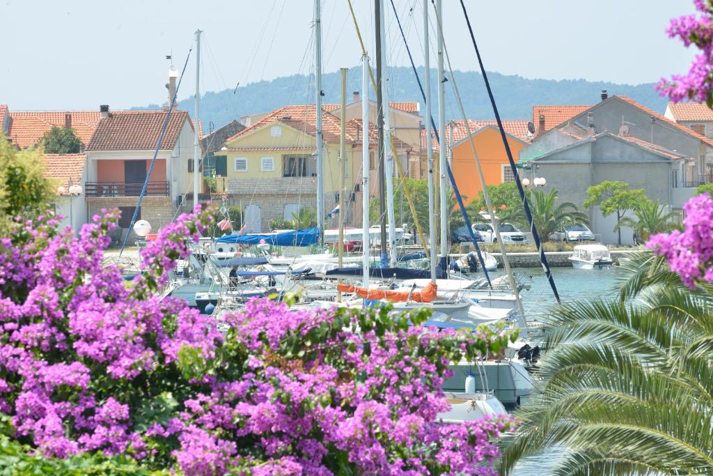 eine Gruppe von Booten, die in einem Hafen mit rosa Blumen angedockt sind in der Unterkunft Apartment Velika obala in Bibinje