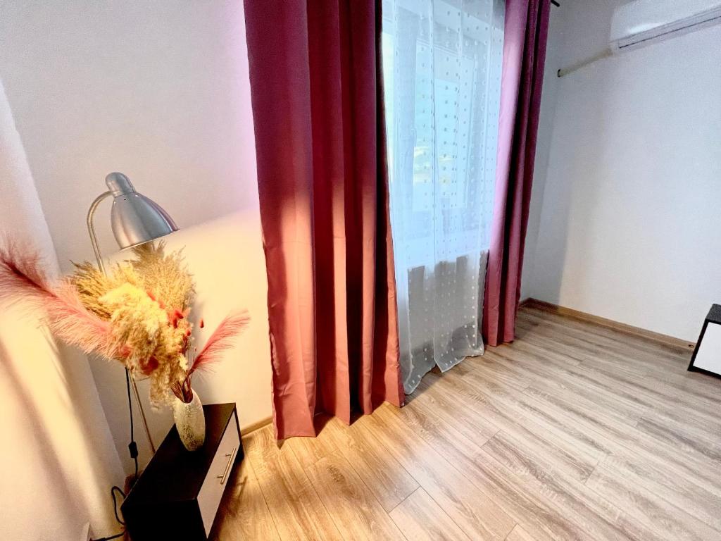 een kamer met een lamp en een raam met rode gordijnen bij WOW Park Drumul Taberei apartment in Boekarest