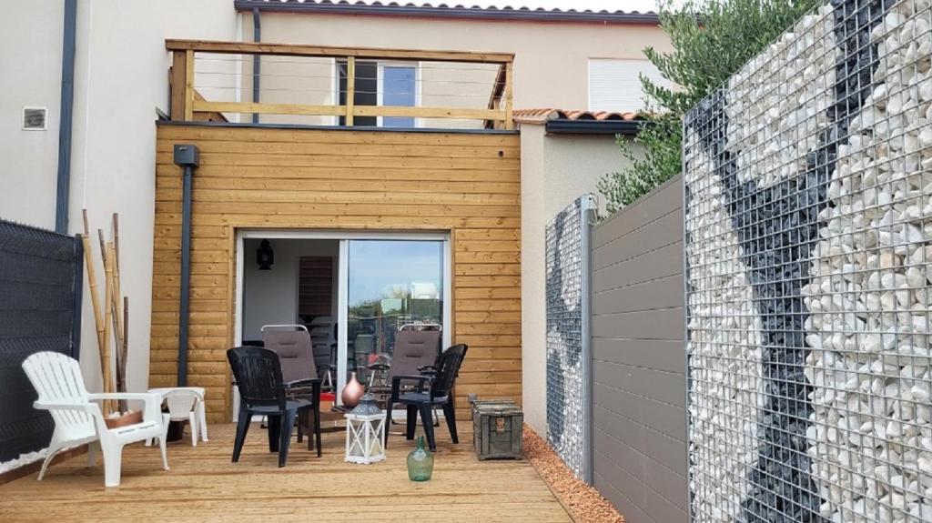 d'une terrasse avec des chaises noires et un mur en briques. dans l'établissement Gîte Du Soleil Maison lumineuse avec terrasse solarium parking privé, à Sorède