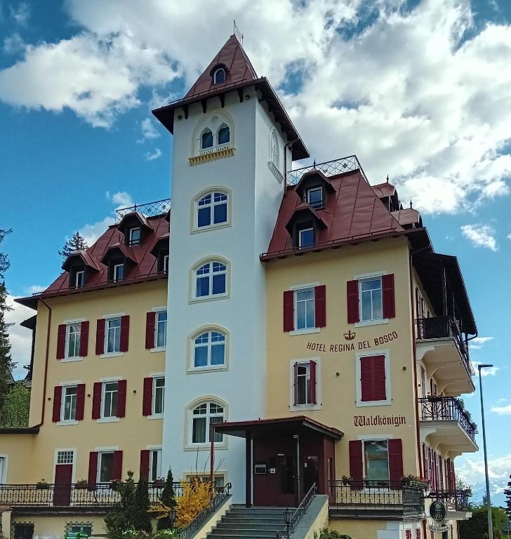a building with a clock tower on top at Hotel Regina del Bosco in Ronzone