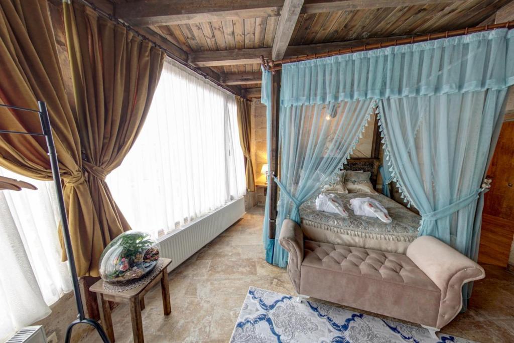 a bedroom with a canopy bed with blue curtains at Cappadocia Alaz Cave Otel in Nevşehir