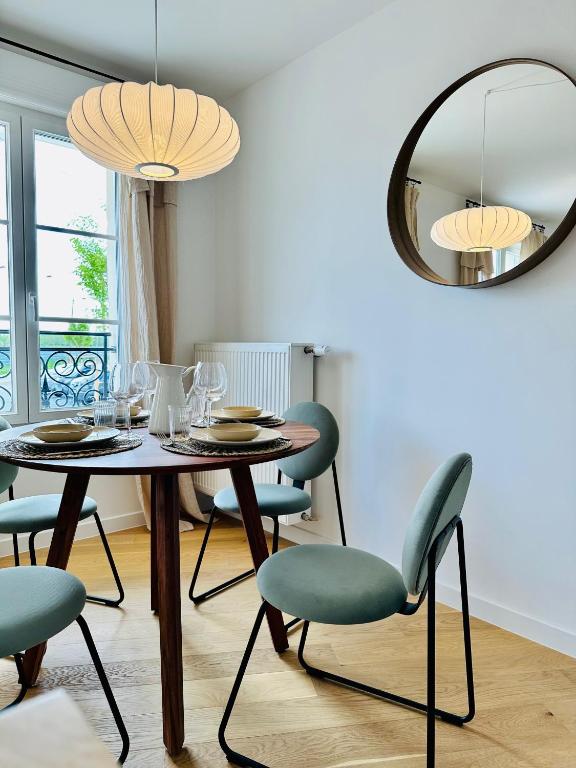 une salle à manger avec une table, des chaises et un miroir dans l'établissement Cosy Apartment / Disneyland / Val d'Europe, à Serris