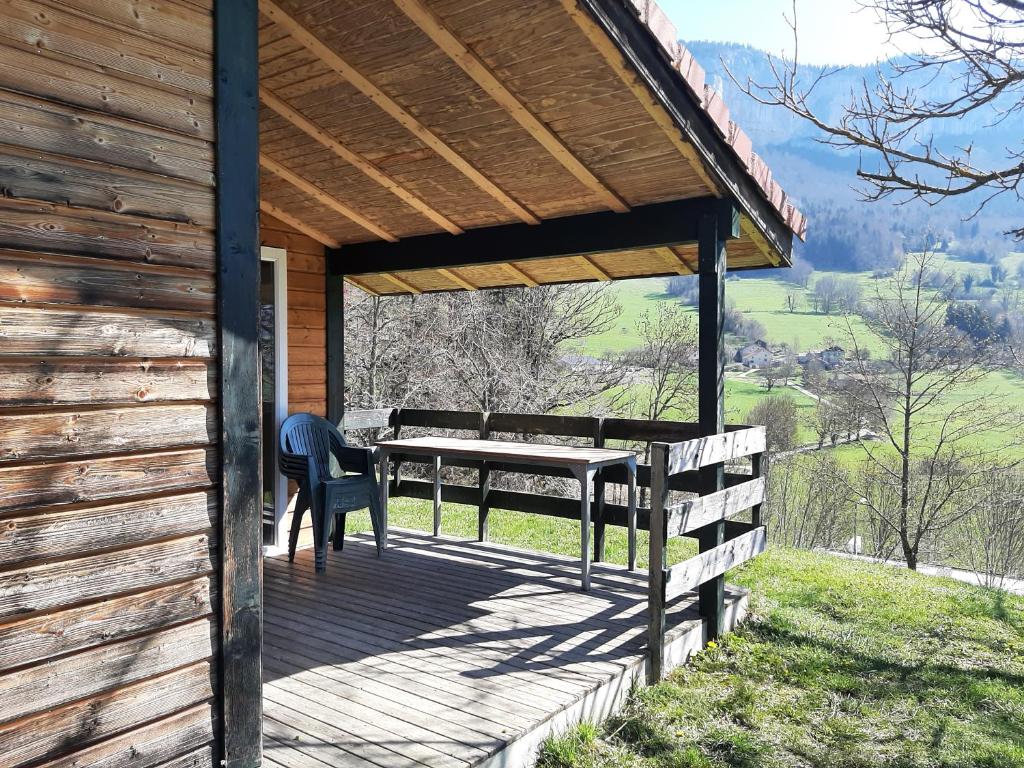 a wooden porch with a table and a bench at chalet du camping la Porte St Martin in Saint-Martin-en-Vercors