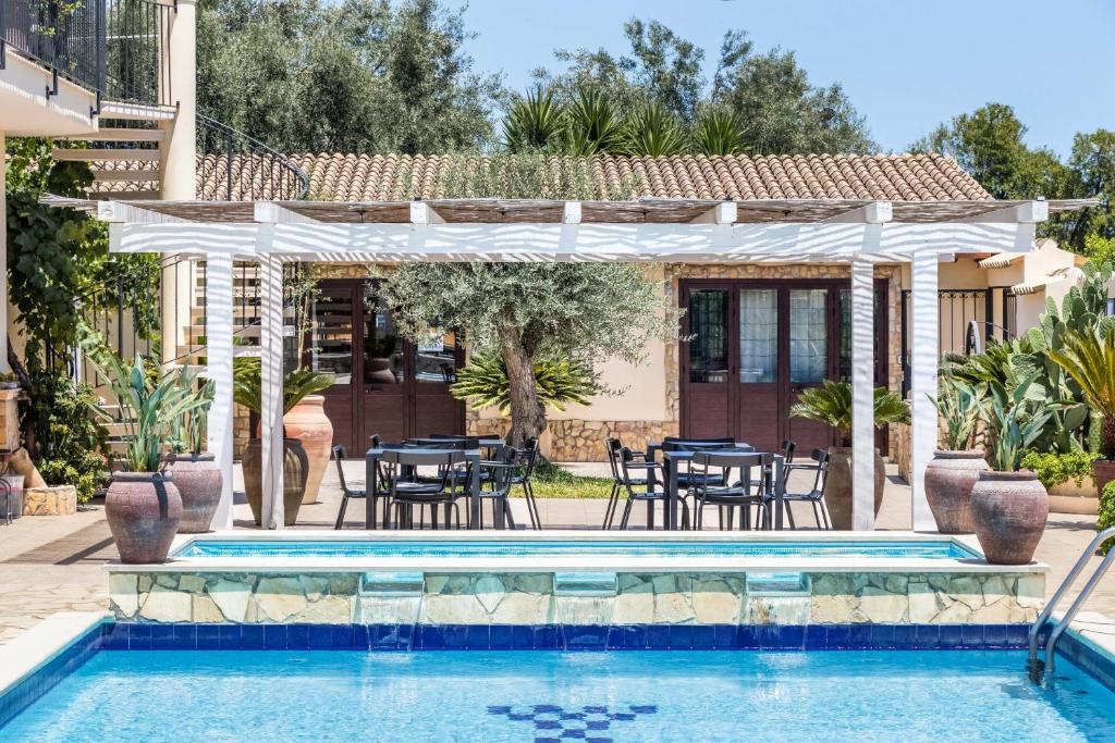 a pool with tables and chairs in front of a house at Villa Felicia in Noto