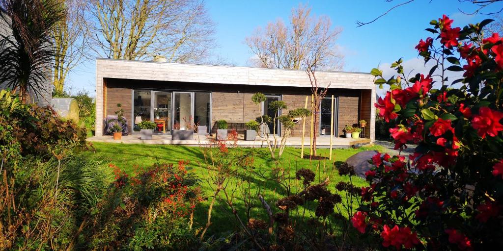 a small house in a garden with red flowers at Belle maison récente proche des plages in Kermaria-Sulard