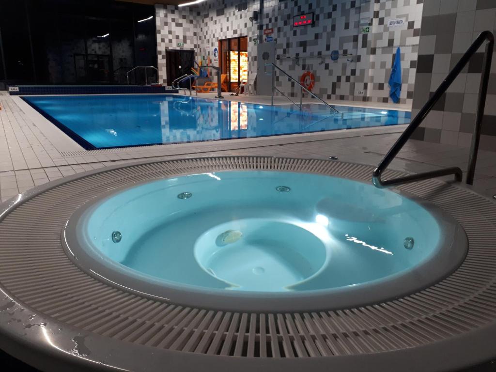 a jacuzzi tub in front of a swimming pool at Apartamenty nad morzem & SPA BEST HOME 5 Mórz in Sianozety