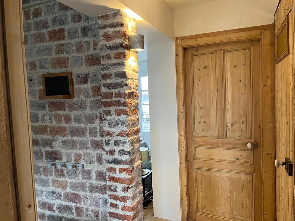 un couloir avec un mur en briques et une porte en bois dans l'établissement Lumineux appartements à 100m plage, à Berck-sur-Mer