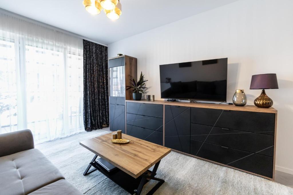 een woonkamer met een tv en een bank en een tafel bij Red Bridge Apartament in Dziwnów