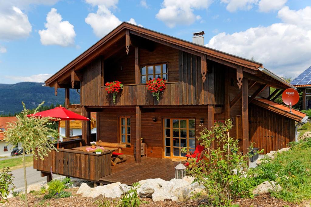 ein großes Holzhaus mit Blumen auf dem Balkon in der Unterkunft Ferienhaus Hirschkopf in Mauth