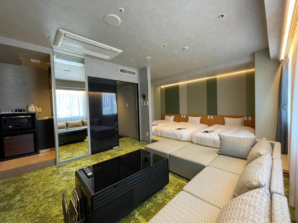 1 dormitorio con cama, sofá y TV en Matsue New Urban Hotel, en Matsue