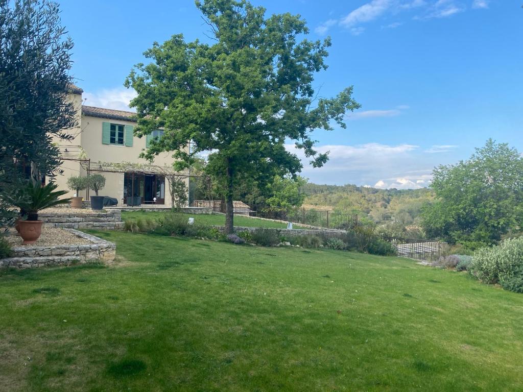 une cour avec une maison et un arbre dans l'établissement Mas des Grands Chenes Uzes a 8km, à Aubussargues