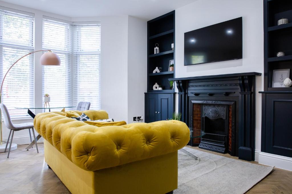 Designer Cardiff Apartments في كارديف: أريكة صفراء في غرفة المعيشة مع موقد