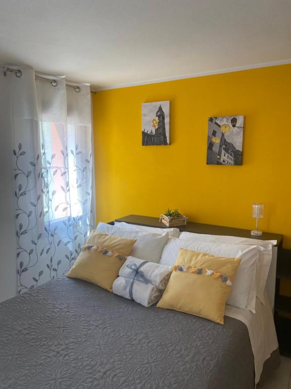 a bedroom with a large bed with a yellow wall at LAGUNA BLU Camera SOLE con terrazza panoramica in comune in Chioggia