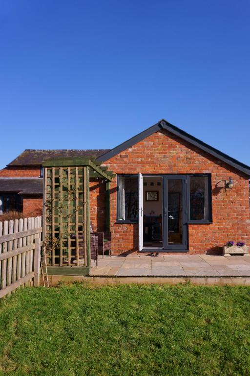 uma casa de tijolos com uma porta e uma cerca em Cwm Lodge, an idyllic retreat in the heart of Herefordshire! em Hereford